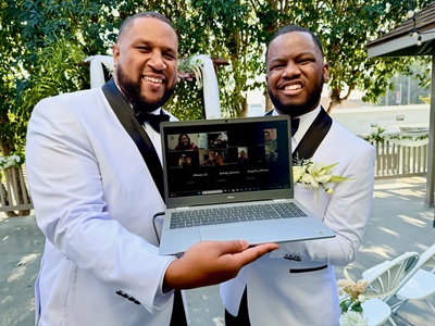 couple holding a computer for a zoom wedding